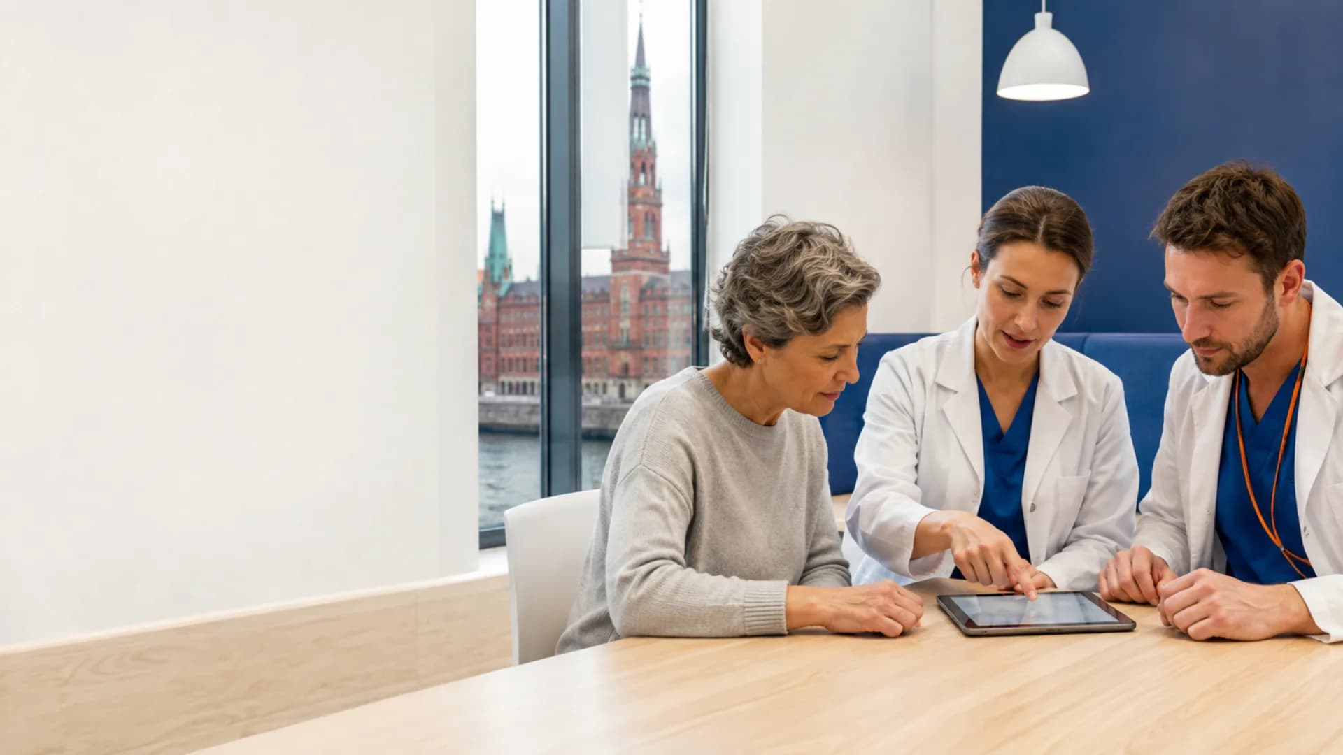 Two medical specialists planning connected care with a patient beside a Hamburg window